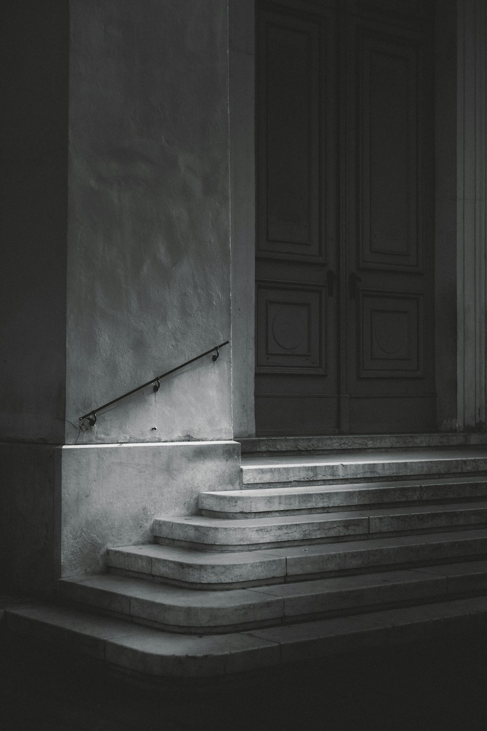 porta di legno bianca accanto alla scala in cemento grigio