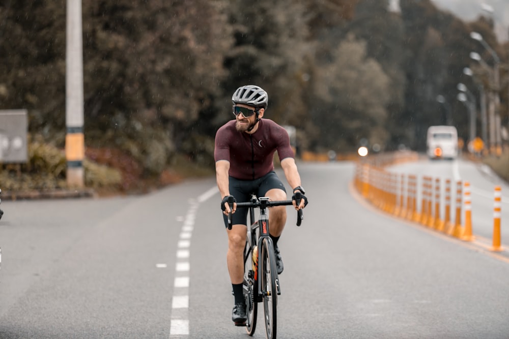 Hombre con camiseta sin mangas roja montando en bicicleta de carretera negra durante el día