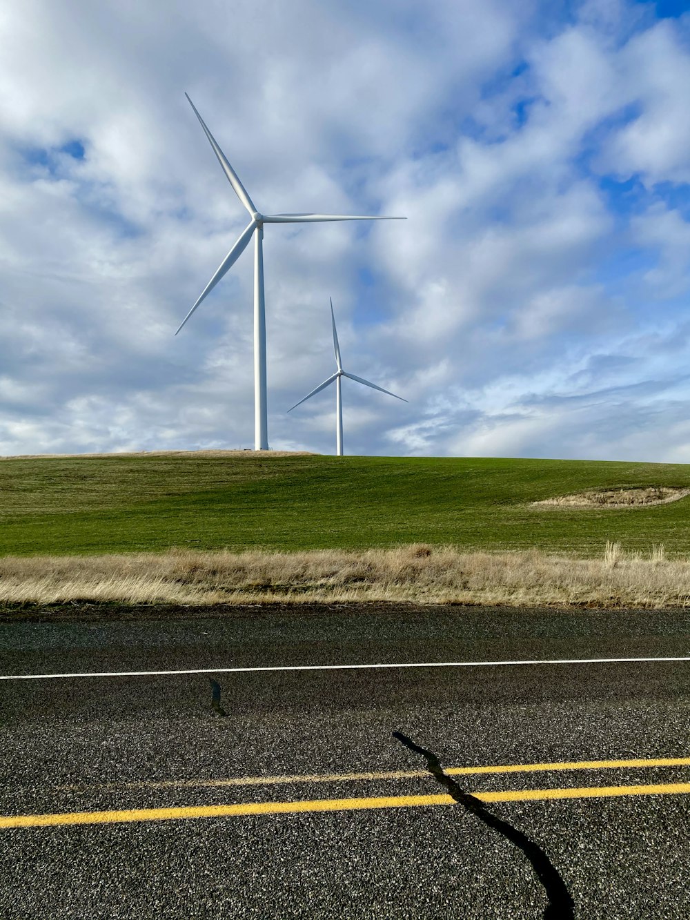 white wind turbines on green grass field under blue and white sunny cloudy sky during daytime