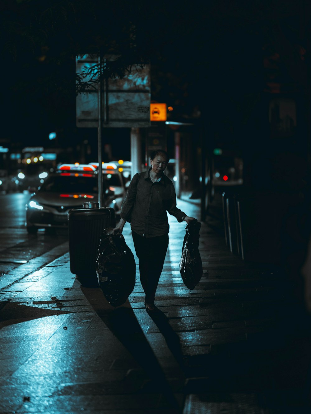 man in black jacket and black pants walking on sidewalk during night time