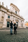 man and woman standing in front of white concrete building during daytime