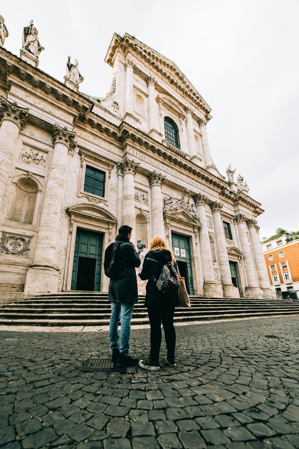 man and woman standing in front of white concrete building during daytime