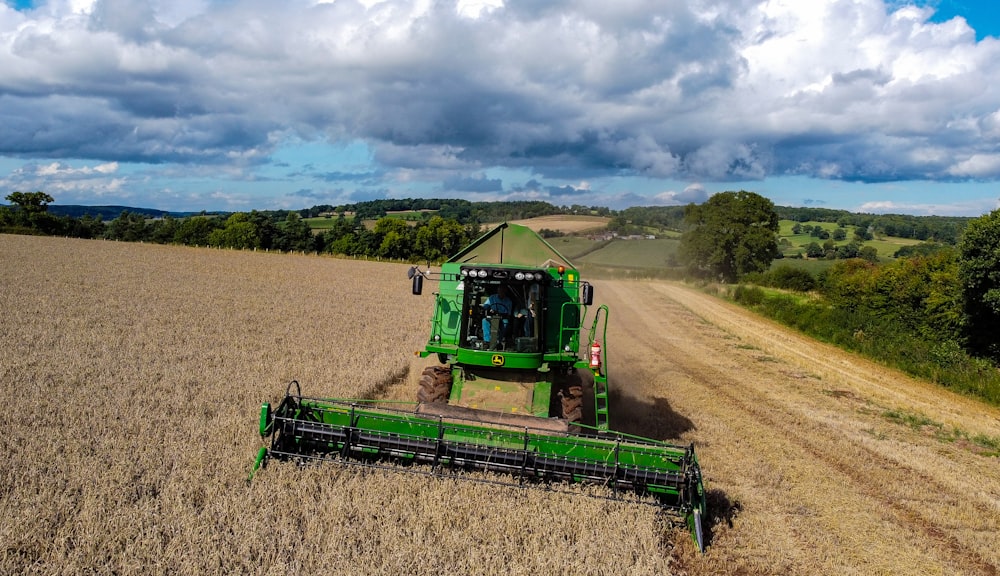 tracteur vert et noir sur un champ brun sous un ciel nuageux pendant la journée