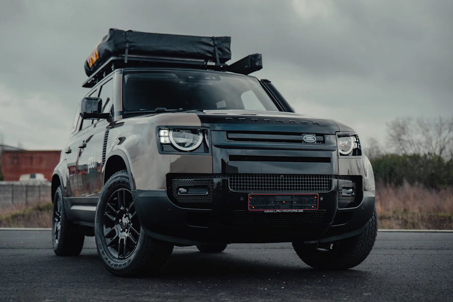 Two-tone Land Rover Defender with roof rack on a country road