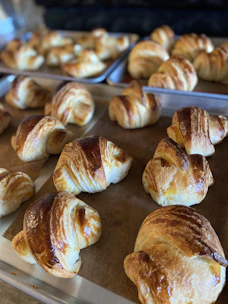 Golden croissants cooling on a rustic wooden tray bathed in morning light.