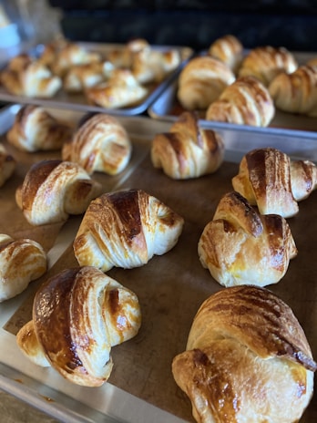 Warm golden croissants fresh out of the oven on a rustic wooden tray.