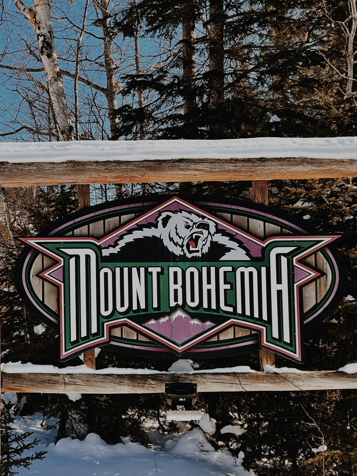 A ski resort sign in snow on a winter day