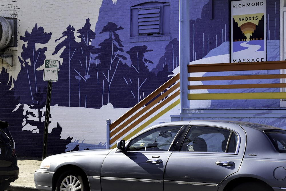 white coupe parked beside blue and white painted wall