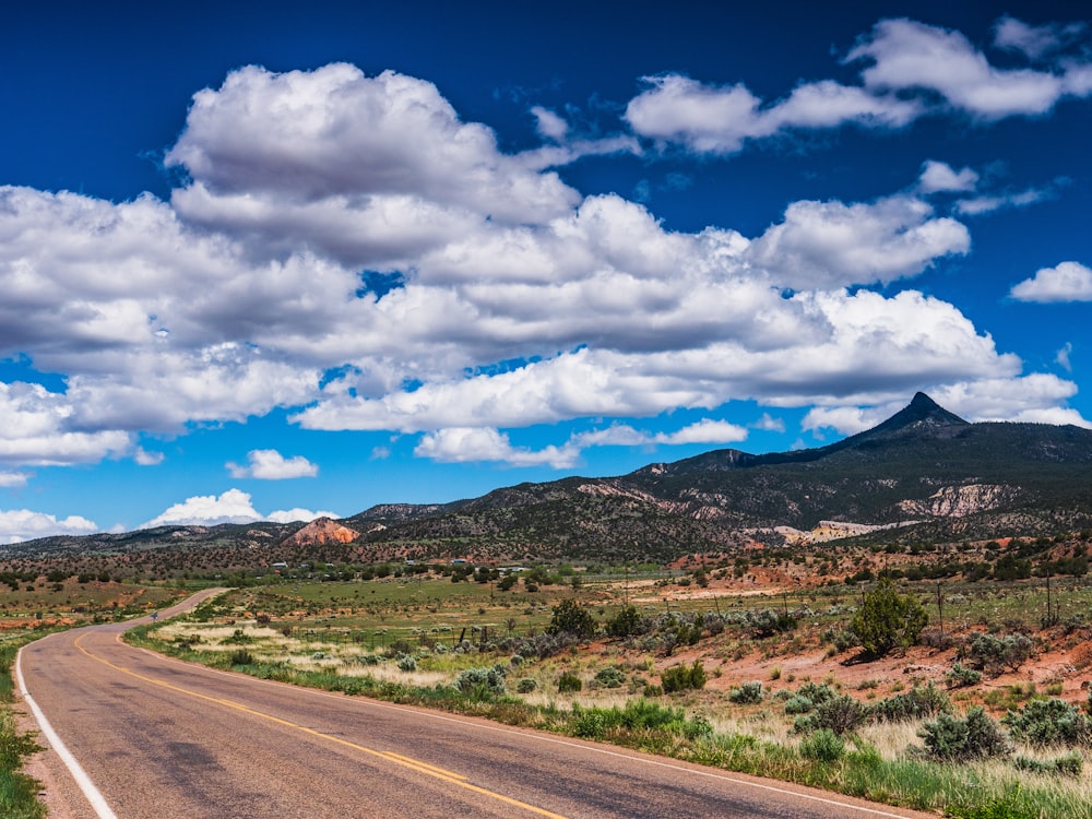 gray asphalt road under blue and white cloudy sky during daytime