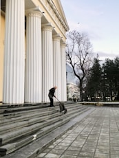 man in black jacket and black pants walking on sidewalk during daytime