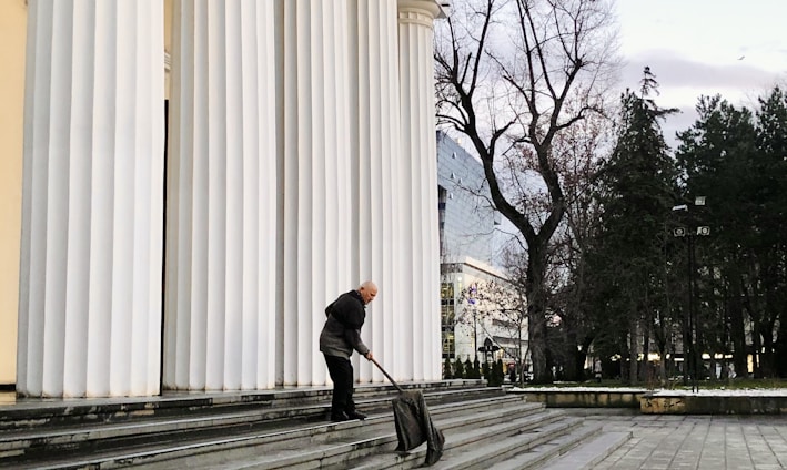 man in black jacket and black pants walking on sidewalk during daytime