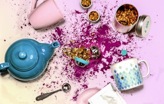 blue ceramic teapot beside white ceramic mug and stainless steel spoon