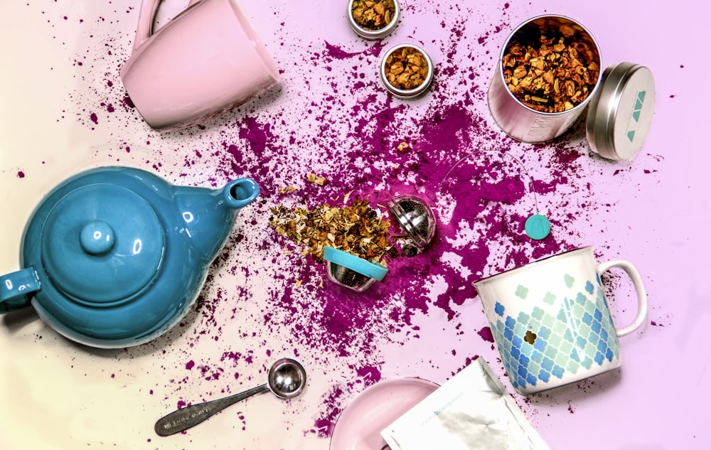 blue ceramic teapot beside white ceramic mug and stainless steel spoon