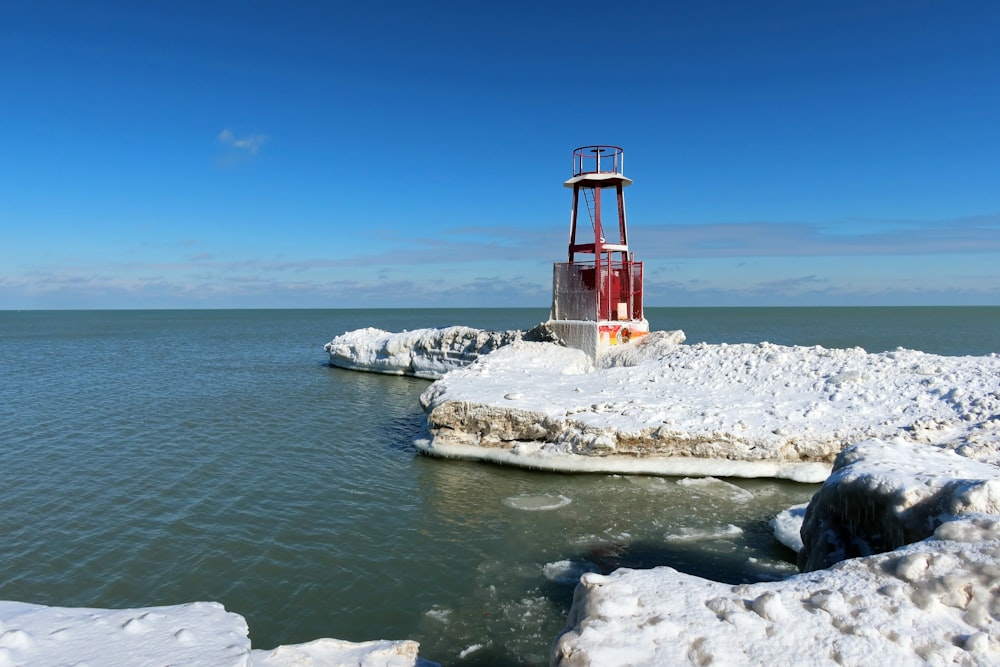 red and white lighthouse on white rock formation near body of water during daytime