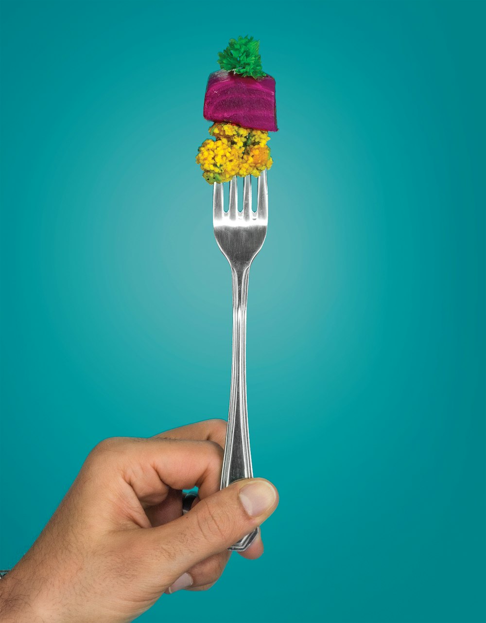 紫と黄色のアイスクリームが入ったステンレス製のフォークを持つ人