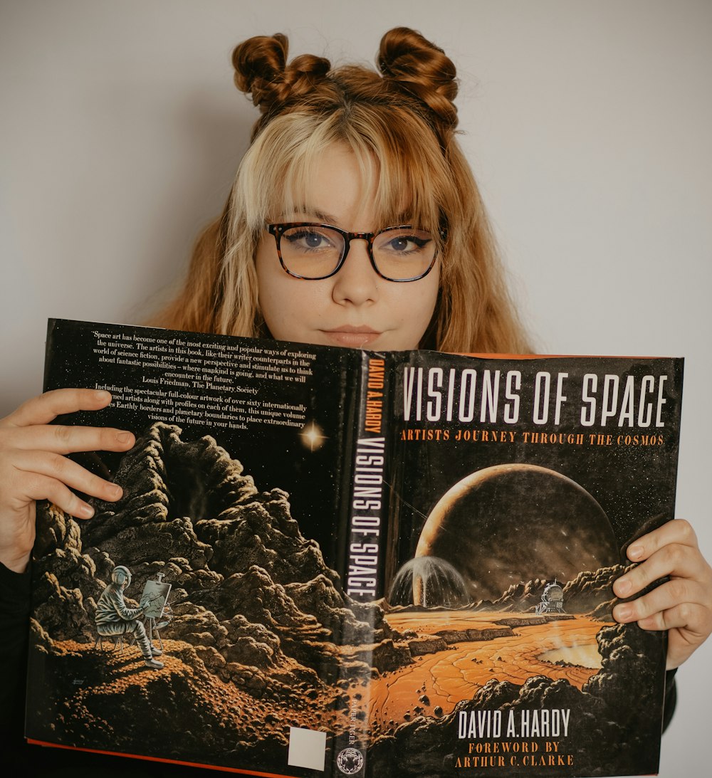 woman in black framed eyeglasses holding a book