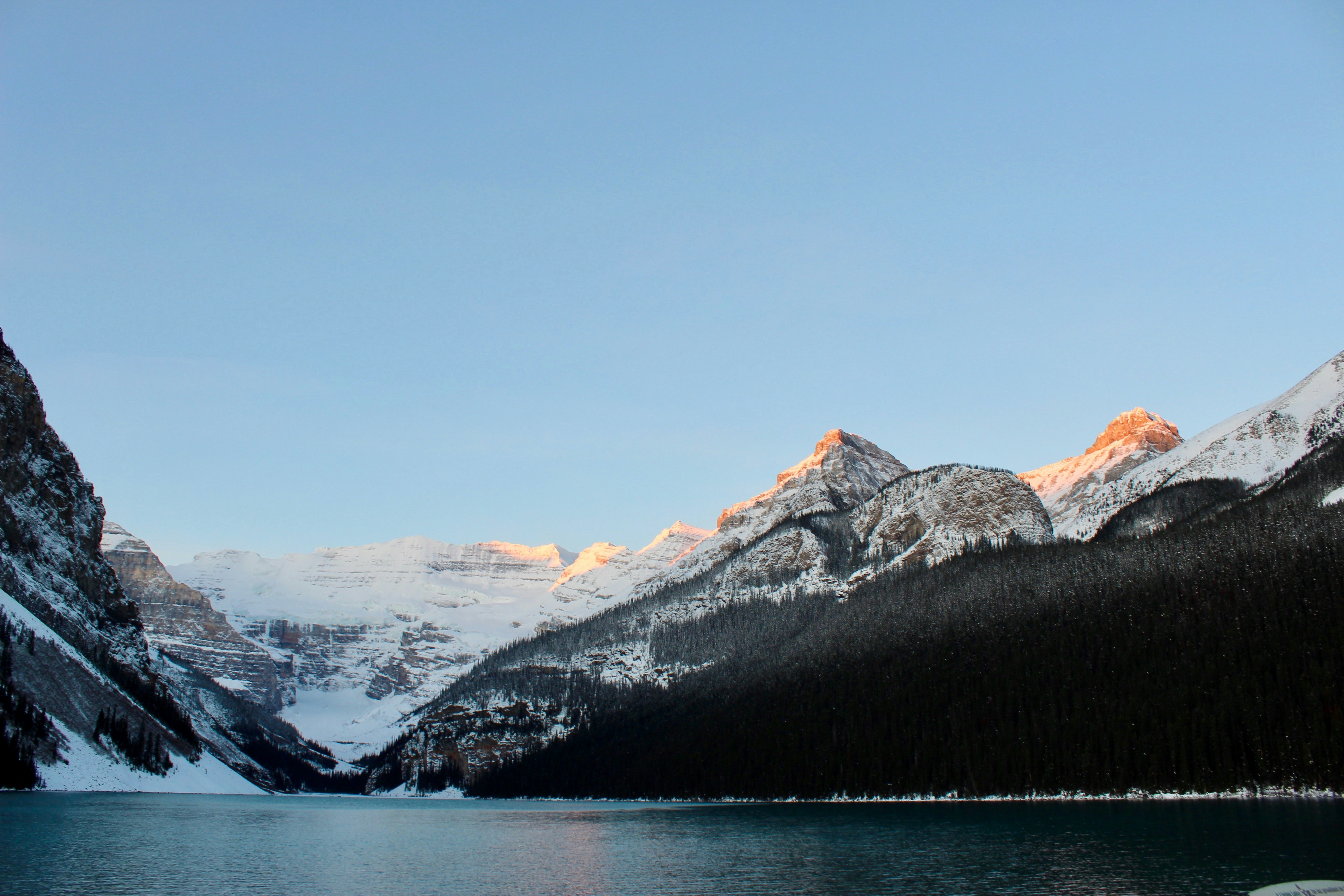 snow covered mountain near body of water during daytime