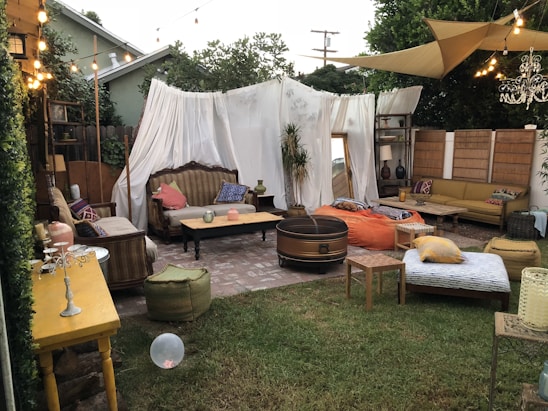 A beautifully styled outdoor wedding lounge area featuring plush sofas and elegant tables under soft lighting.