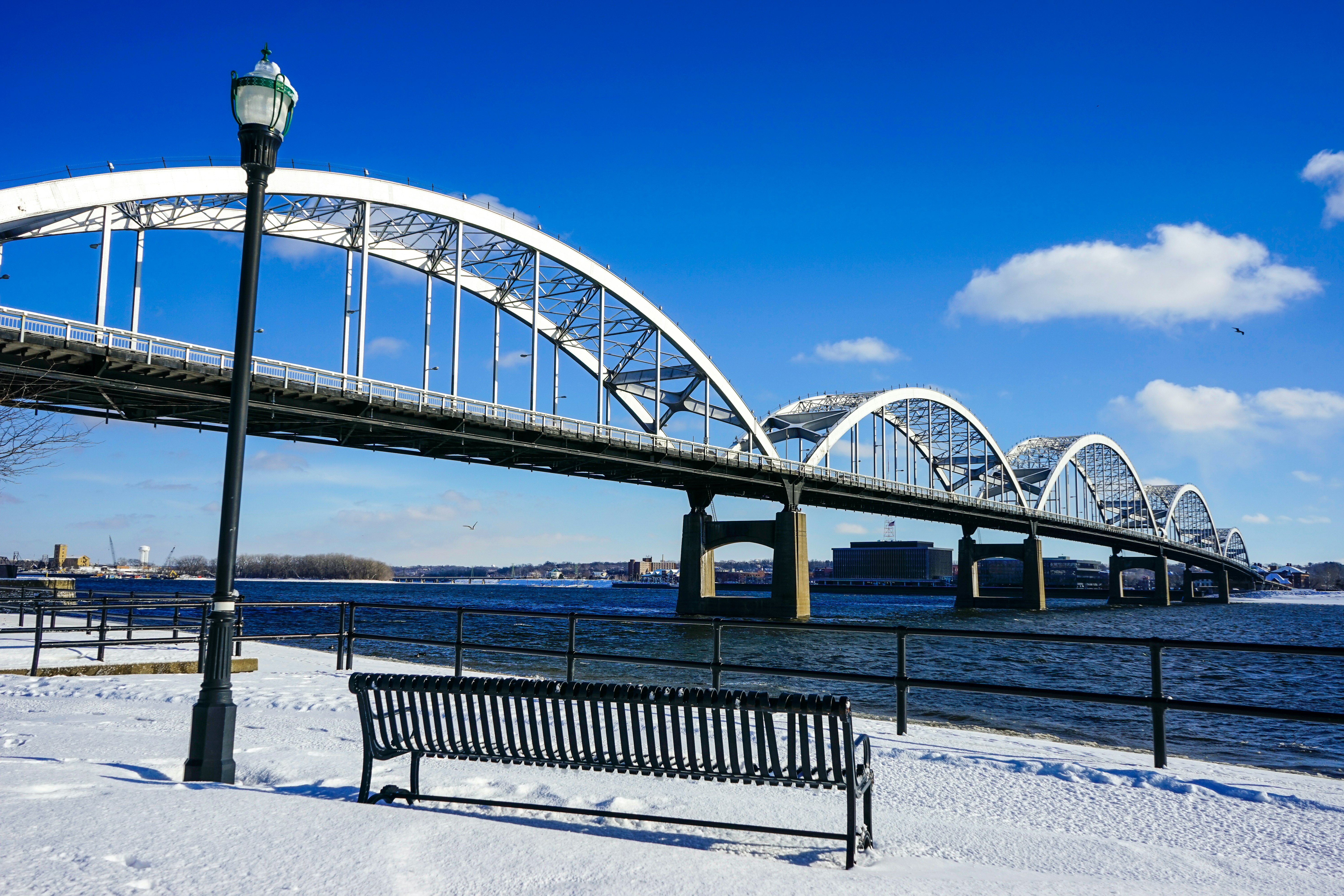 black metal bench on snow covered ground under blue sky during daytime