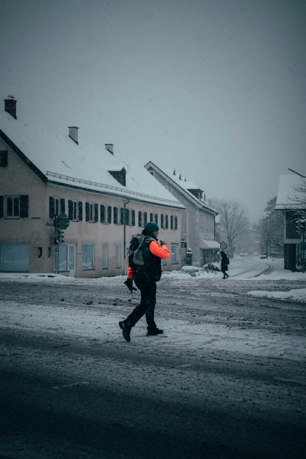 persona in giacca nera e pantaloni neri che cammina sulla strada coperta di neve durante il giorno