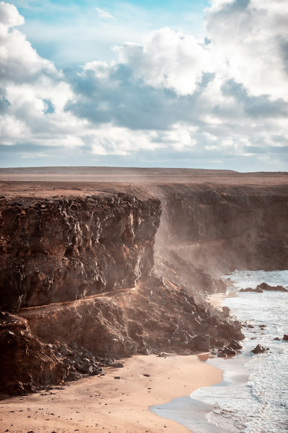Formazione rocciosa marrone vicino al mare sotto il cielo blu durante il giorno