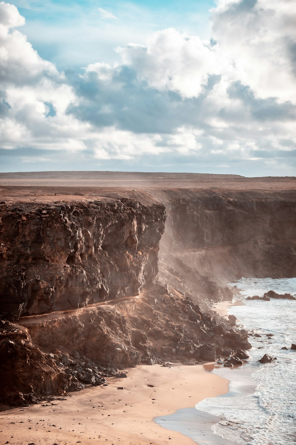 brown rock formation near sea under blue sky during daytime