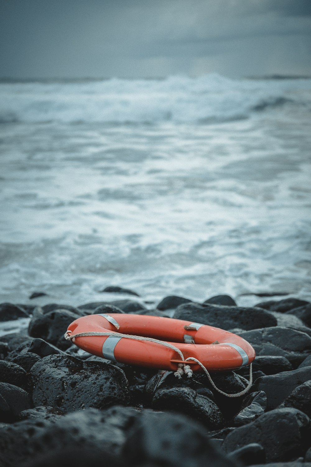 red inflatable ring on black rock near body of water during daytime