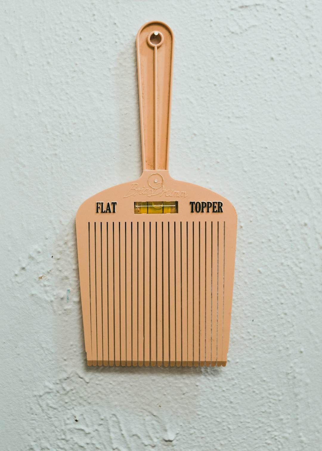 brown wooden hair comb on white painted wall