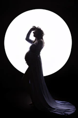 Silhouette of a pregnant woman against a soft glowing backdrop.