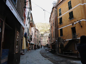Narrow cobblestone street lined with pastel-colored houses and hanging lanterns in the evening light