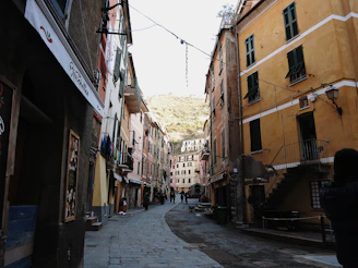 Narrow cobblestone street lined with pastel-colored houses and hanging lanterns in the evening light