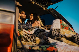 couple smiling and sitting in a car trunk  