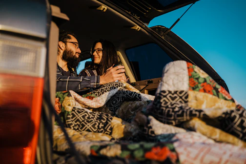 couple smiling and sitting in a car trunk  