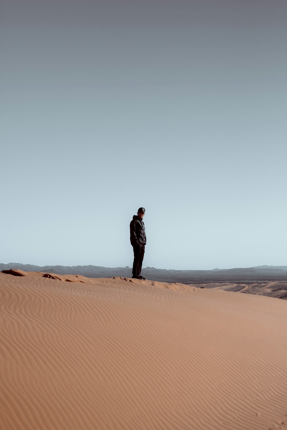昼間の砂漠に立つ黒いドレスの女性