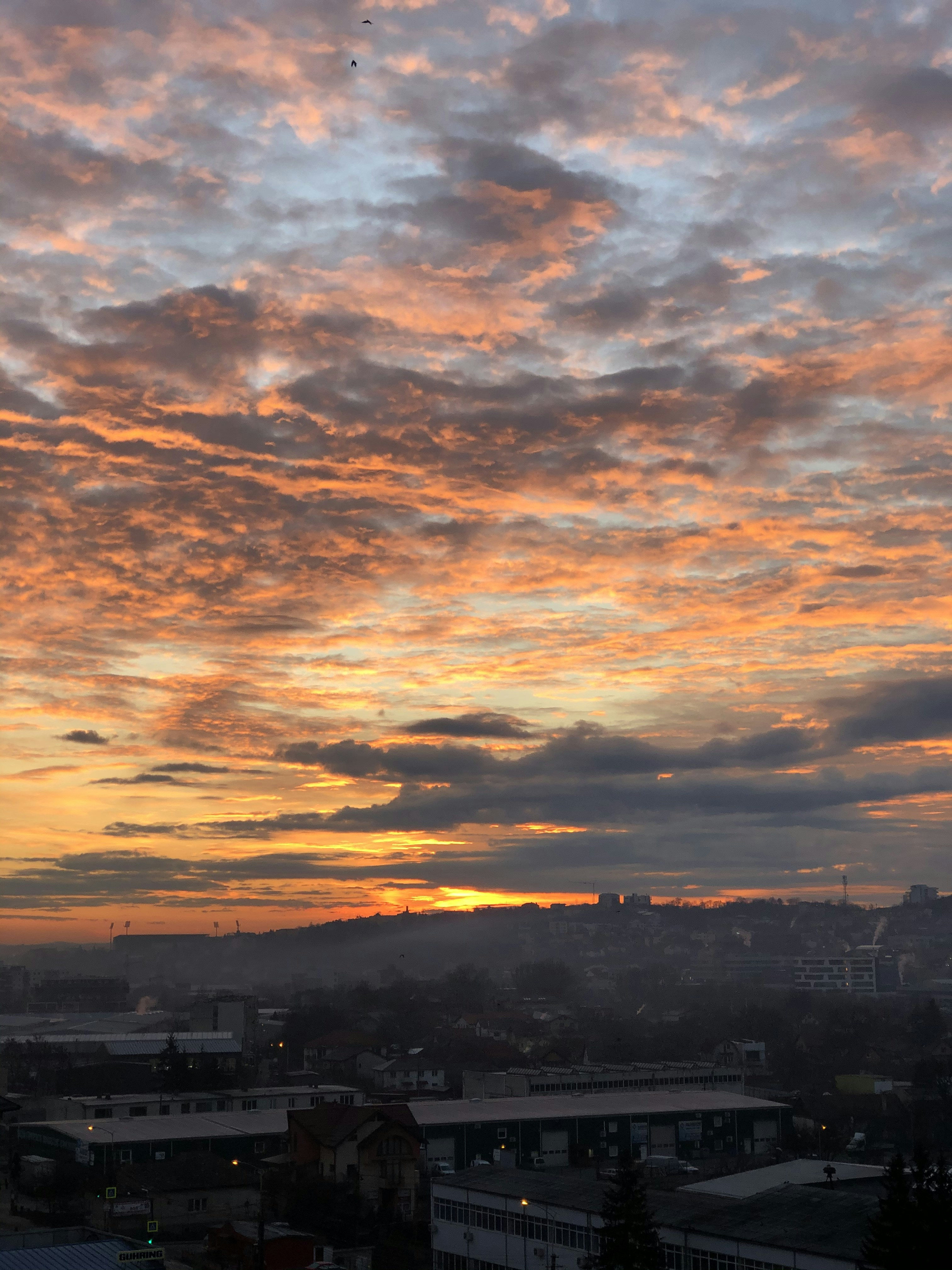 silhouette of buildings under cloudy sky during sunset