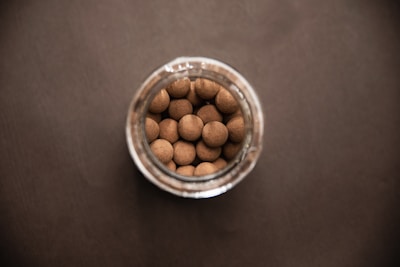 Macro shot of uniform starch-based pellets spilling gently from a stainless steel container.