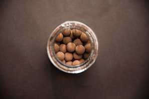 A close-up of a jar filled with golden soil and pearls.
