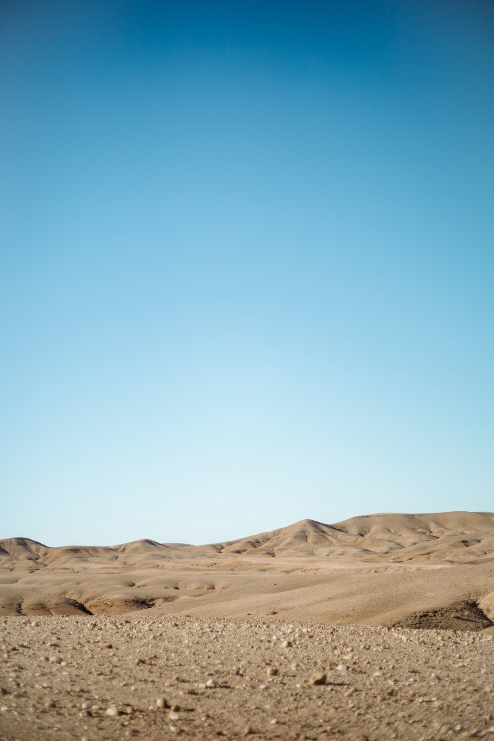 areia marrom sob o céu azul durante o dia
