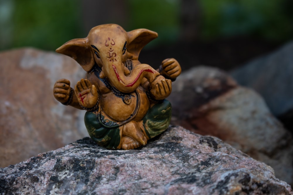 brown ceramic elephant figurine on gray rock