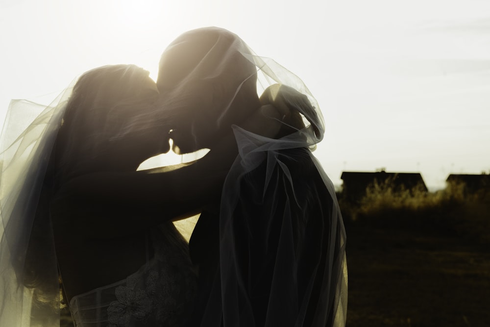 couple kissing on grass field during sunset