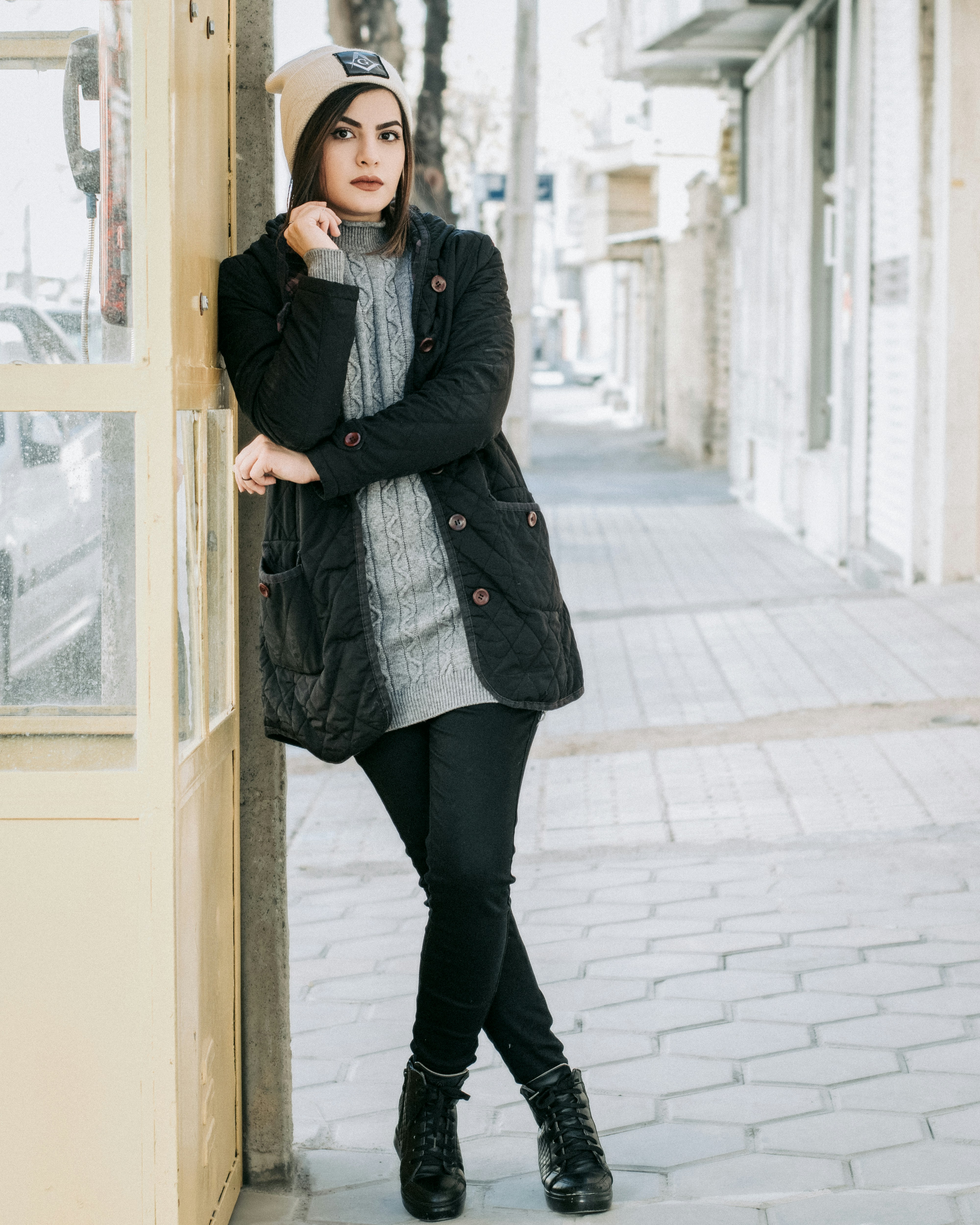 woman in black coat standing beside glass window