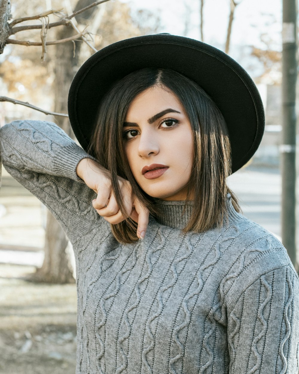 Una mujer joven con un sombrero negro y un suéter gris