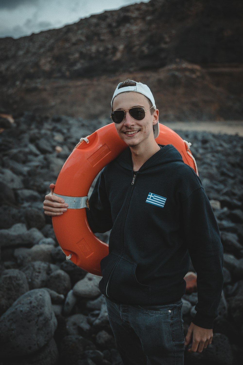 man in black and orange zip up jacket wearing orange life vest holding orange inflatable ring