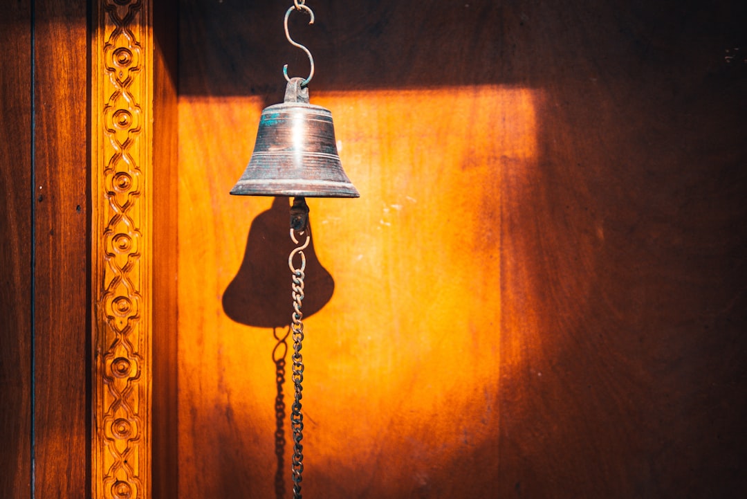 silver bell on brown wooden wall