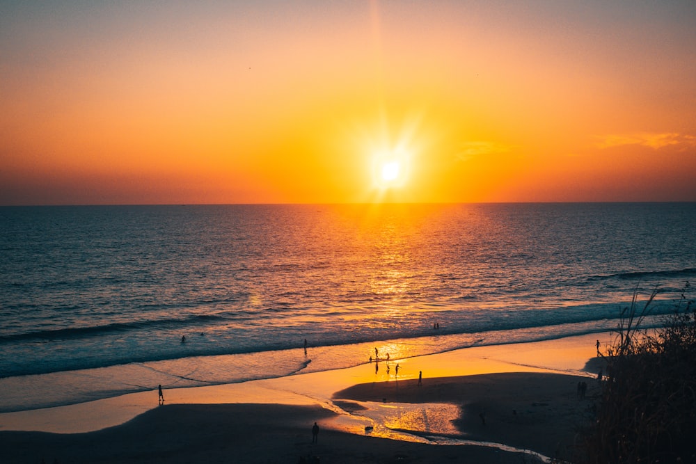 people walking on beach during sunset