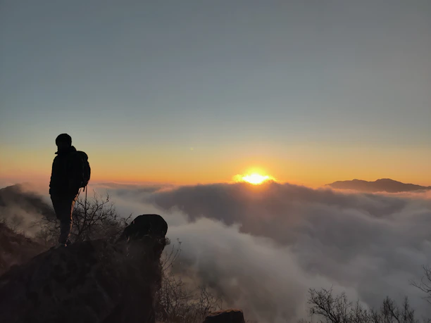A serene sunrise over the Himalayas with a lone traveler meditating on a mountain ledge.