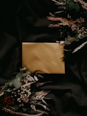 A luxurious gold foil invitation set against a dark velvet background.
