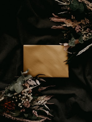 A luxurious gold foil invitation set against a dark velvet background.