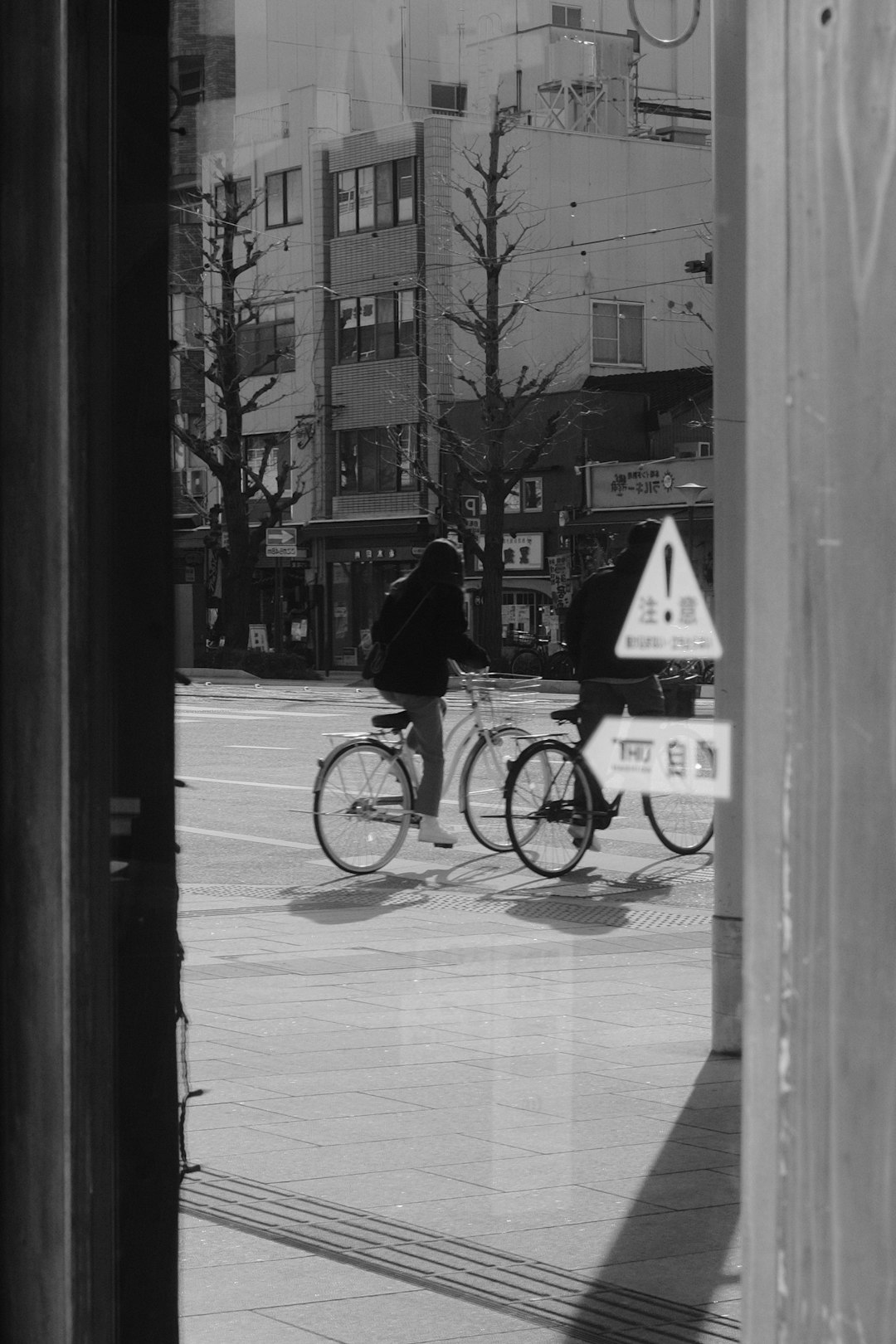 grayscale photo of woman riding bicycle on sidewalk