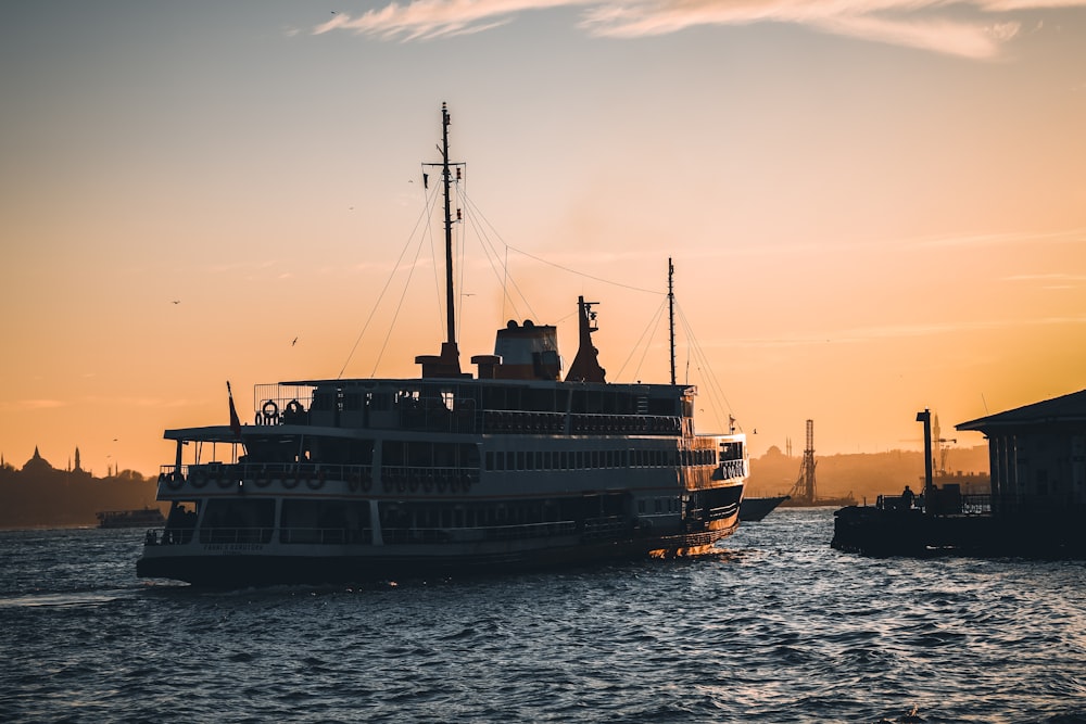 black and white ship on sea during sunset